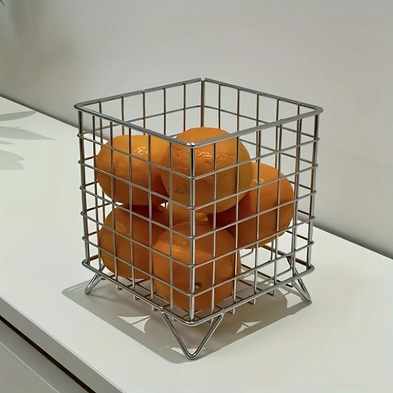 Chrome wire storage basket holding oranges on a kitchen counter